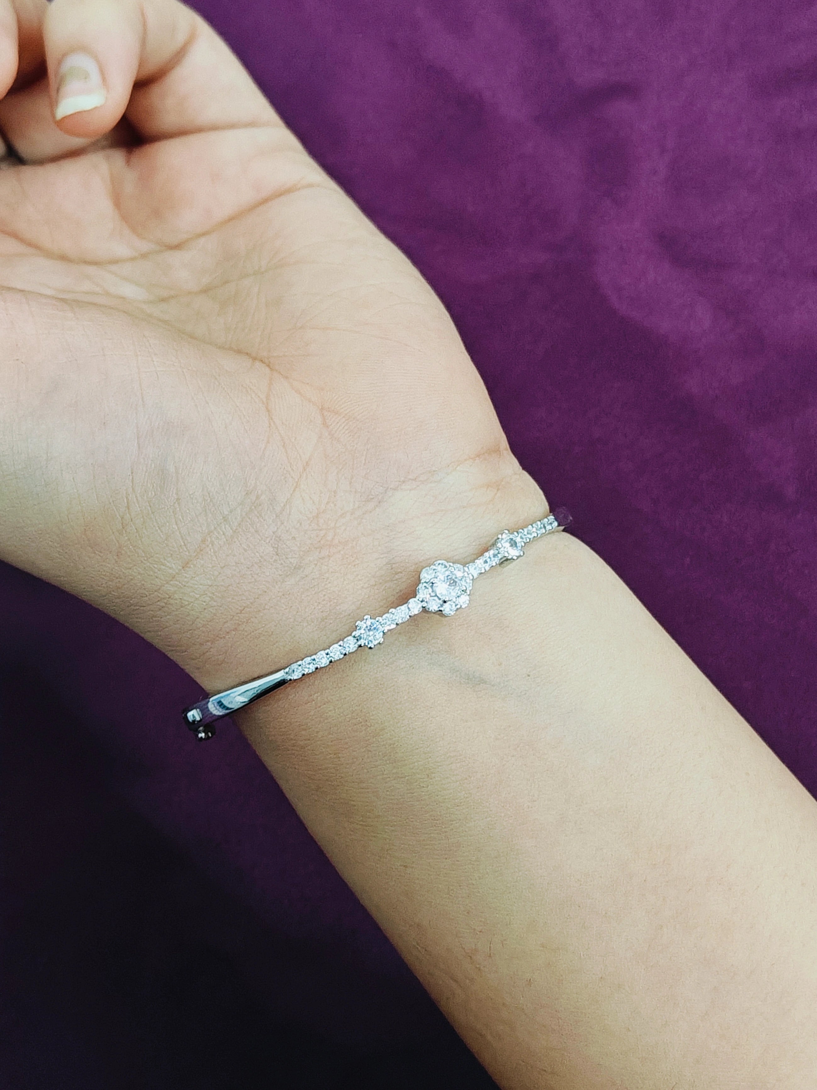 Silver bracelet on a wrist with a purple background